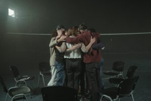 group of people supportively hugging one another