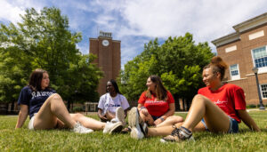 4 Radford University Students sitting on campus lawn talking